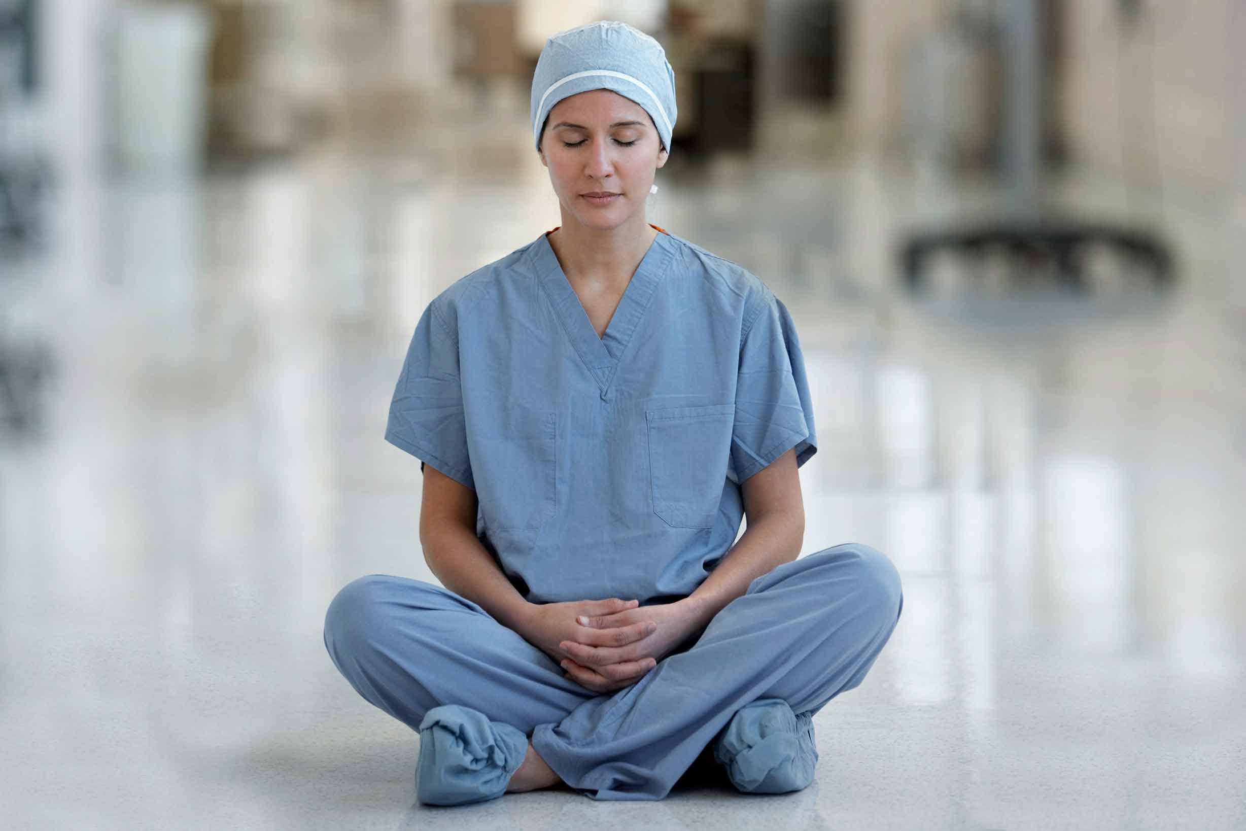 Nurse meditating in a hospital hallway